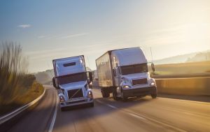 two semi-trucks driving on the highway, representing our freight factoring services to the transportation industry.