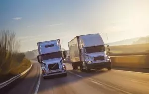 two semi-trucks driving on the highway, representing our freight factoring services to the transportation industry.